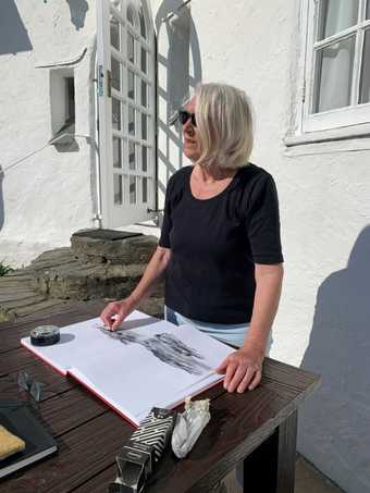 Susan McCall standing up looking out whilst drawing the landscape using charcoal