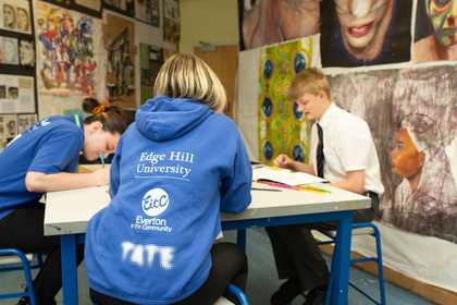 Students and Tackling the Blues ambassador sit at a table surrounded by students' artworks