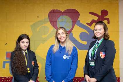 2 students stand either side of a young Tackling the Blues ambassador