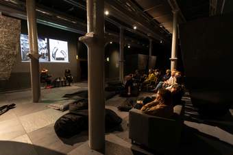 A photograph of two speakers talking to each other in front of an audience in Tate Liverpool's exhibition space on the ground floor