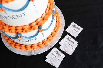 A photograph of a cake with orange and blue icing.