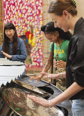 A group of people play steel pans with their hands