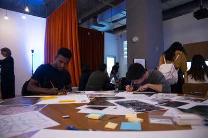 Two people working at a table that has post it notes and images scattered across it