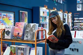 A woman reads a book inside the Tate Modern Main Shop