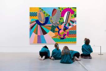 Children sitting in front of a large artwork in a gallery