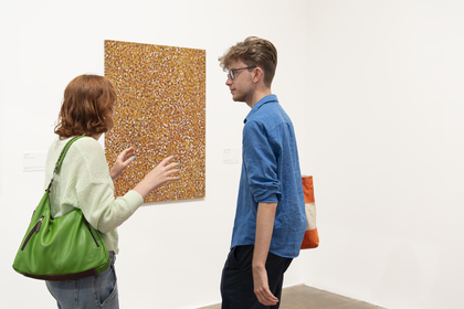 Two people stand in front of 'Untitled (Alhalker)' by Emily Kam Kngwarray.