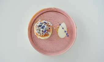 Pink earthenware plate against a pale background with a haut-cuisine dish, a souffle and a sorbet.