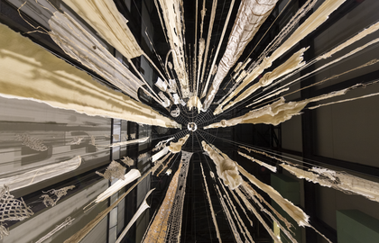 The perspective of standing in the middle of Cecilia Vicuna's Brain Forest Quipu Turbine Hall Commission, looking directly up so that the strands of material stretch out to the sides of the frame.