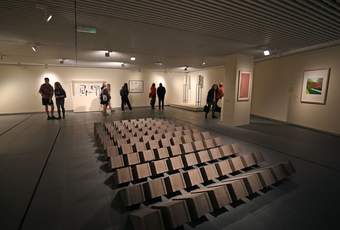 A photograph of visitors looking at artworks in Tate Liverpool's Brickworks display