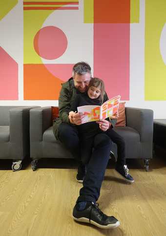 Child and dad reading a book in the Clore Studio