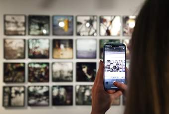 A photograph of a visitor taking a photo of an artwork at Tate Liverpool + RIBA North.