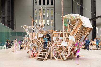 Children climbing on a wooden and canvas carriage in a large gallery
