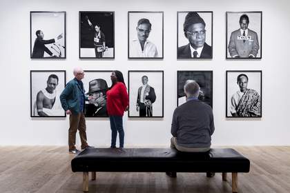 Three people looking at a wall of artworks