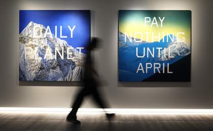 A photograph of a person walking past two artworks on the wall.