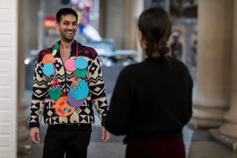 A person laughing wearing a handmade necklace of large colourful paper circles