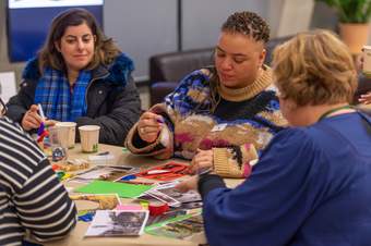 A group of teachers sit at a table making a collage.