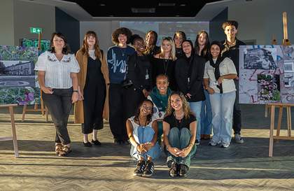 A photograph of a group of young people surrounded by their own artworks in the background.