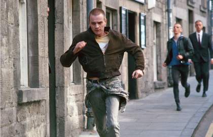 A still from the film Trainspotting showing a young man running down a street.