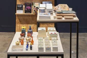 A photograph of a shop display at Tate Liverpool, featuring small vases, books and jewellery.