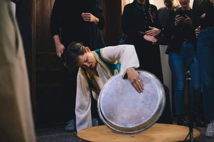 A woman spinning a pan on a wooden table in the middle of a crowd.