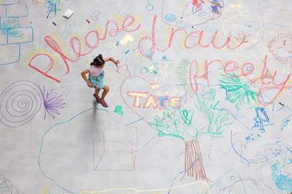 A child skipping over large chalk drawings on a concrete floor