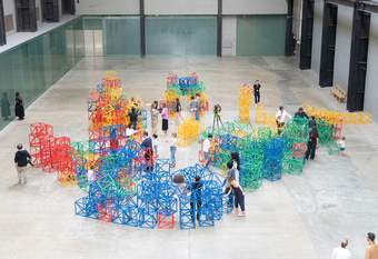 Looking down at people in a large hall playing with colourful plastic sculptures.