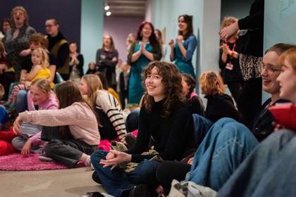 Image shows a group of people at a U Studio festival event. They are sitting together and smiling to the camera.