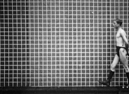 A figure walking in front of a grid in black and white