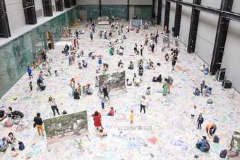 A view looking down at people drawing and writing on the floor of the Turbine Hall.