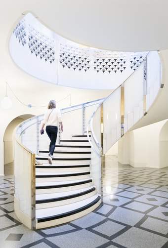A person walking up a large black and white spiral staircase