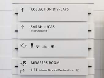 Signs in a gallery giving directions to exhibitions and facilities