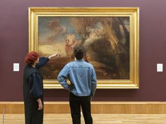 Two people looking at a large painting by JMW Turner