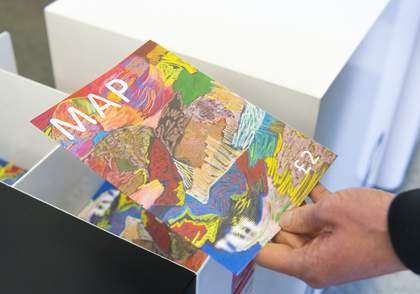 A person's hand picking up a colourful paper map