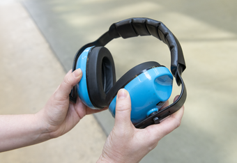 Hands holding a pair of ear defenders