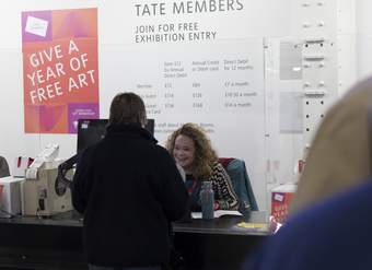 A Ticketing Assistant smiling and speaking to a visitor