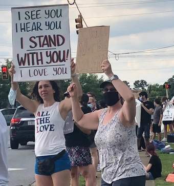 Woman protesting with a sign that reads I See You I Hear You I Stand with You! I Love You