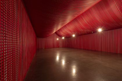 Room-sized installation created with lengths of Royal British Legion Remembrance Poppy Appeal paper negatives, like strips of film, covering the walls and ceiling to create a tent-like structure