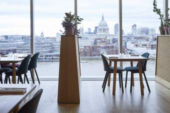 Interior of a restaurant with large windows showing London's skyline