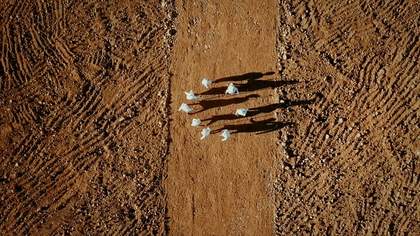 An aerial image of people wearing white outfits, walking in a circle in a field