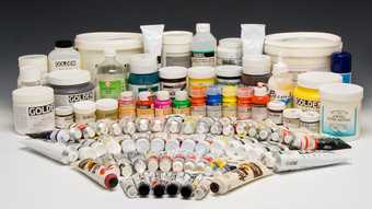 Many pots and tubes of paint in different colours, arranged in a concentric fan shape