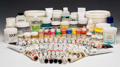 Many pots and tubes of paint in different colours, arranged in a concentric fan shape