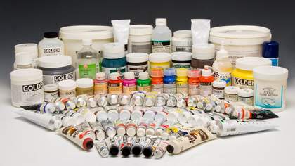 Many pots and tubes of paint in different colours, arranged in a concentric fan shape