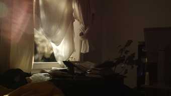 Film still of window curtain of bedroom, light shines through