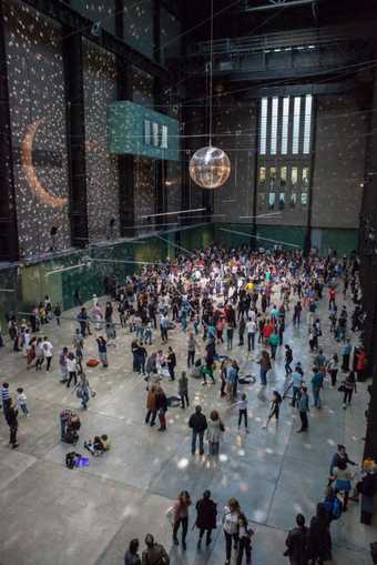 Disco ball and lights fills the turbine hall with dancers and visitors 