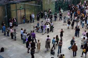 Dancers huddle and move in a disco lit turbine hall