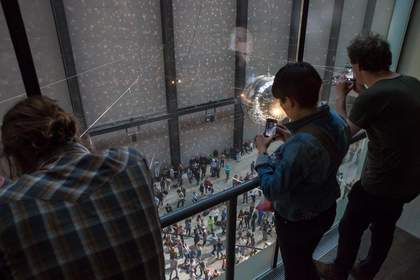 Three people watch the dance performance from a balcany and film on their phones