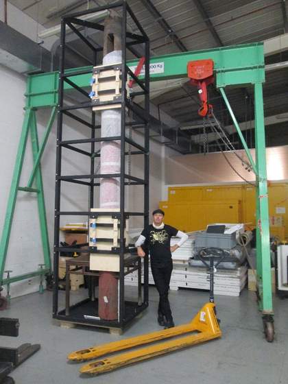 A man stands beside a metal frame around Table and Pillar