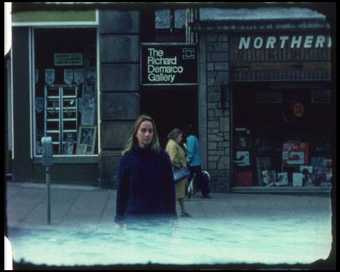 image of a woman standing in front of a few shops