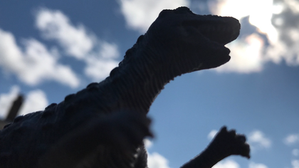 a toy dinosaur looks up at the sky