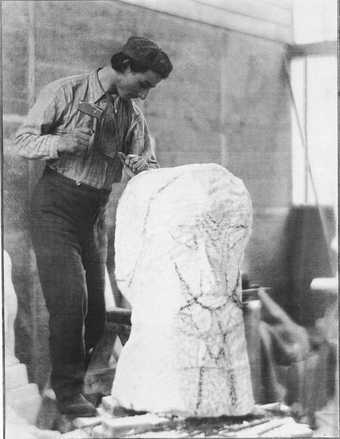 Black and white photograph of Henri Gaudier Brzeska carving hieratic head of Ezra Pound.